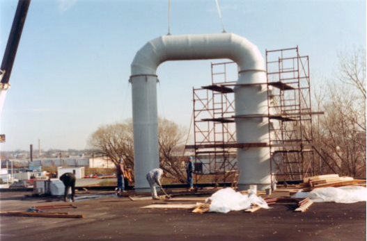 Delta Cooling Towers, Inc. installed an ammonia removal system with off-gas scrubbing to treat a 25gpm process waste water stream containing ammonia. The tower is white and u-shaped into the ground.  There are a couple a workers cleaning up the area around the tower.  