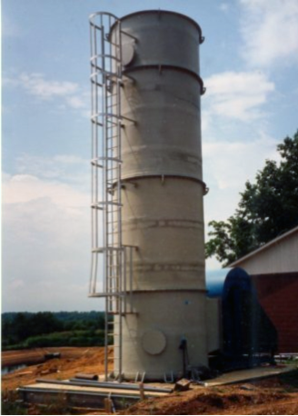 Delta Cooling Towers, Inc. designed and fabricated (1) one beige 9’-0” Diameter x 29’-0” high air stripping tower to treat 70gpm of Ammonia contaminated water at the Coey Tanning Company factory in Wartrace, TN. The tower has a ladder on its side and is next to a building. There is dirt around the tower with a blue, cloudy sky behind it. 